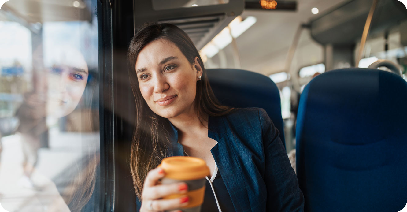 A woman sitting on a train holding a cup of coffee.