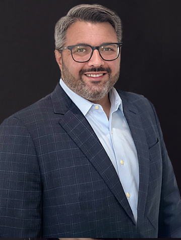 A man wearing glasses and a suit is posing for a photo.